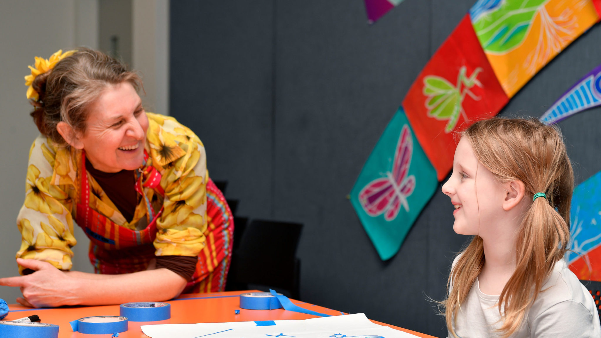 Tutor and child smile at each other during an art workshop.